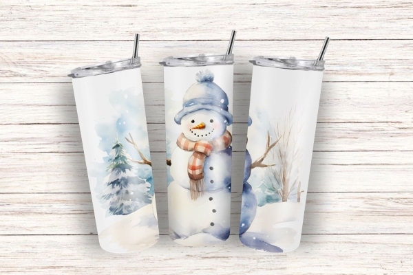 Set von drei Thermobechern mit winterlichem Schneemann-Design und schneebedeckten Bäumen auf Holzuntergrund.